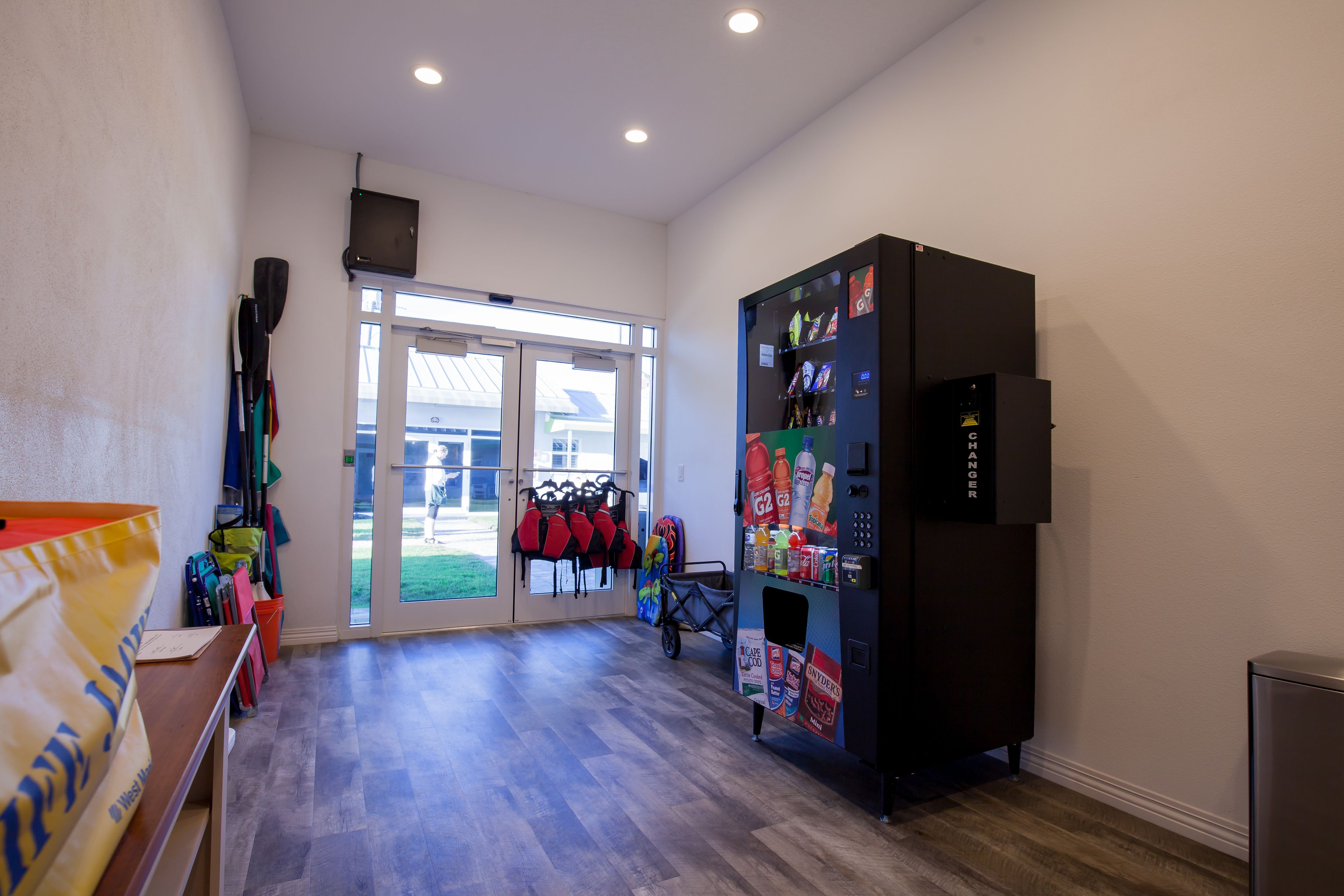 A room with a vending machine, a window with a view, and a door leading outside.