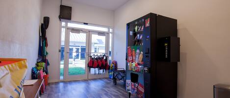 A room with a vending machine, a window with a view, and a door leading outside.