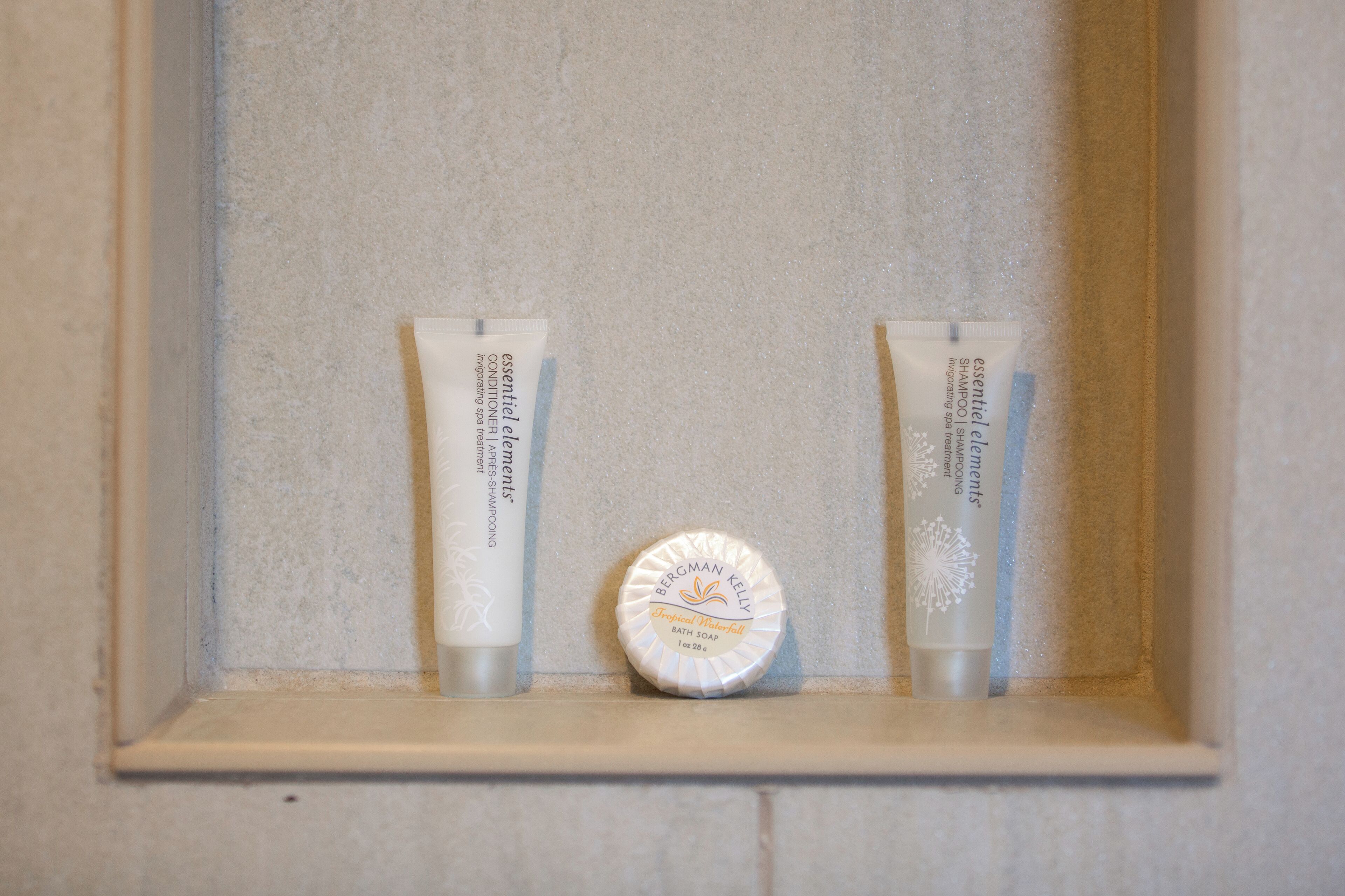 A shelf with two tubes of Bergman Kelly bath soap and a bottle cap.