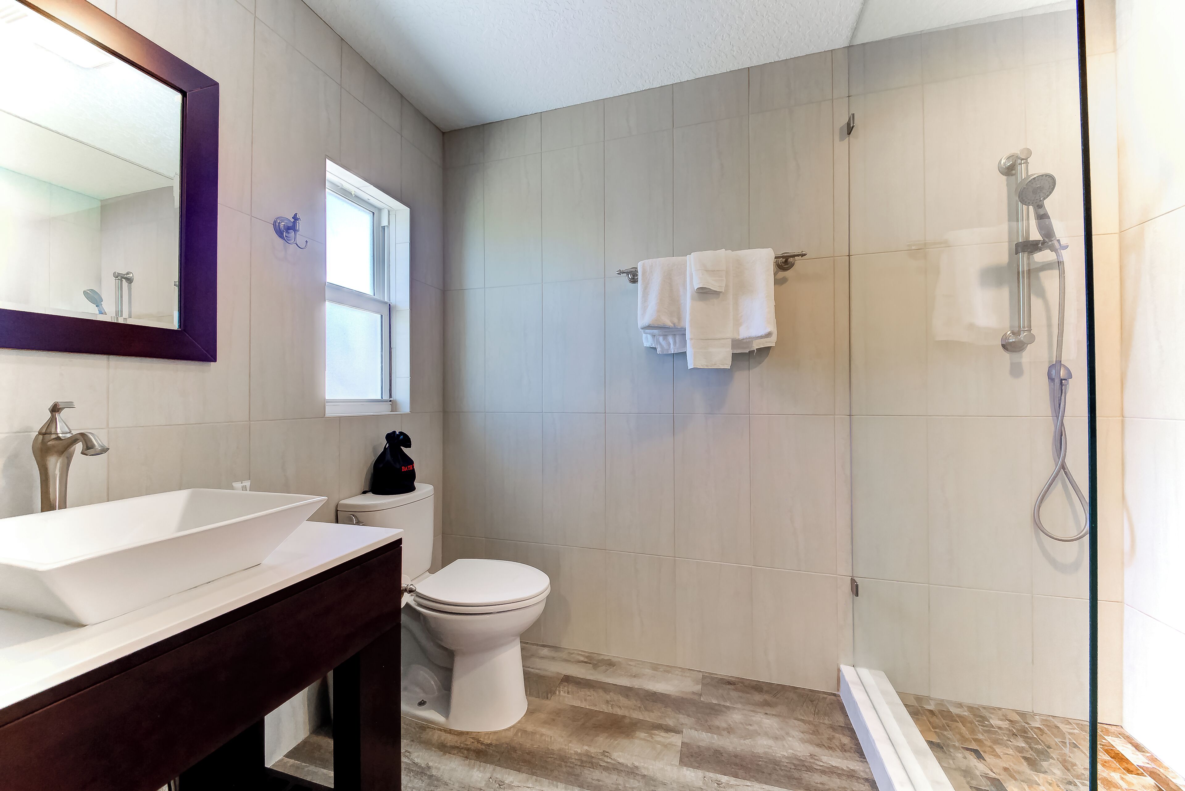 Une salle de bain moderne avec un grand miroir, un lavabo blanc, des toilettes et un espace douche.