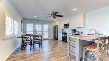 A spacious kitchen with a central island, wooden dining table, and chairs.