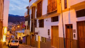 A multi-story building with balconies, a street with cars, and a clear sky. - Cozy Room Cusco (Cusco)
