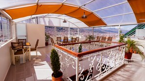 A spacious terrace with a view of a cityscape, furnished with wooden chairs and a table, and a potted plant. - Cozy Room Cusco (Cusco)