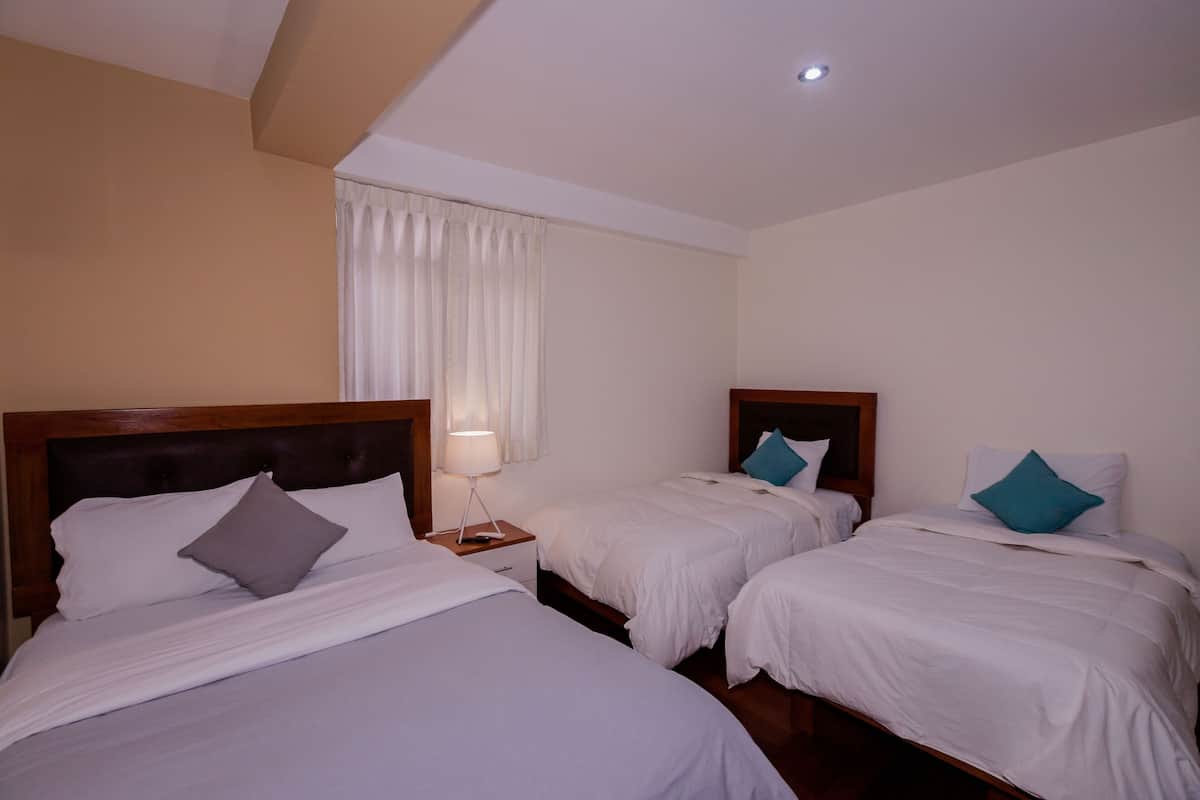 A hotel room with two single beds, each with a wooden headboard, white bedding, and a nightstand with a lamp.