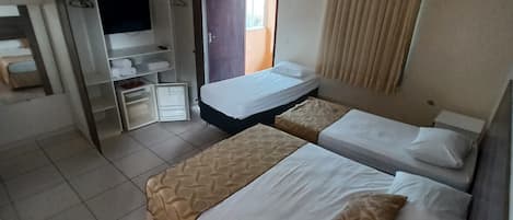 Habitación de hotel con dos camas, televisión, armario y baño.