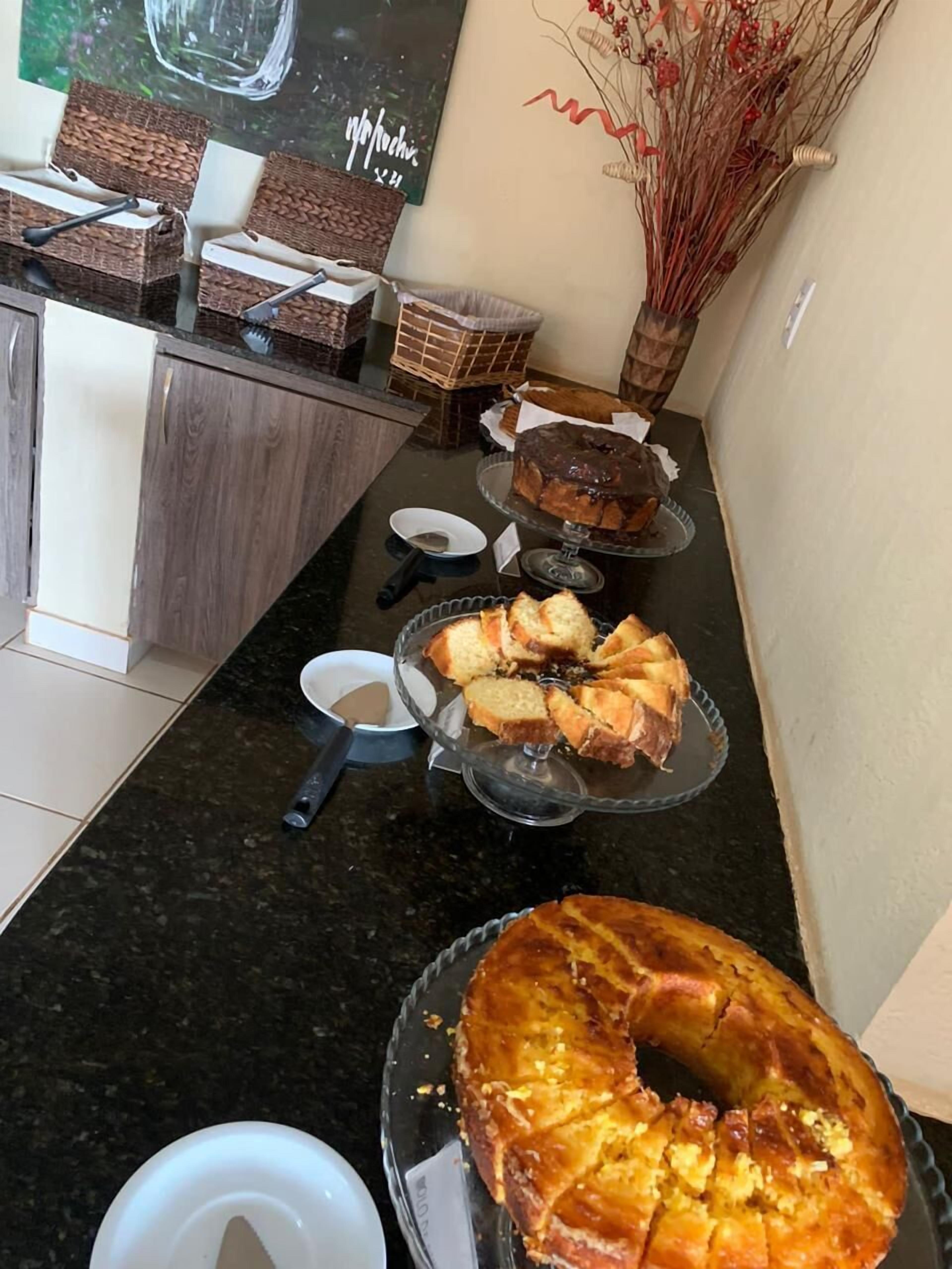A kitchen counter with various baked goods, including a bundt cake and sliced bread, along with a decorative vase and a woven basket.