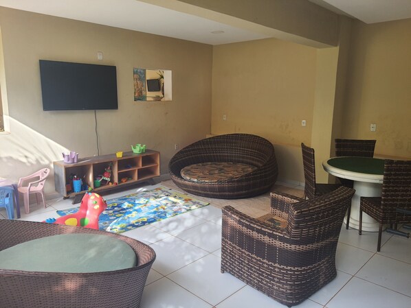 A living room with a television, a sofa, a dining table, and a play mat. - Pousada Porto das Dunas (Aquiraz)