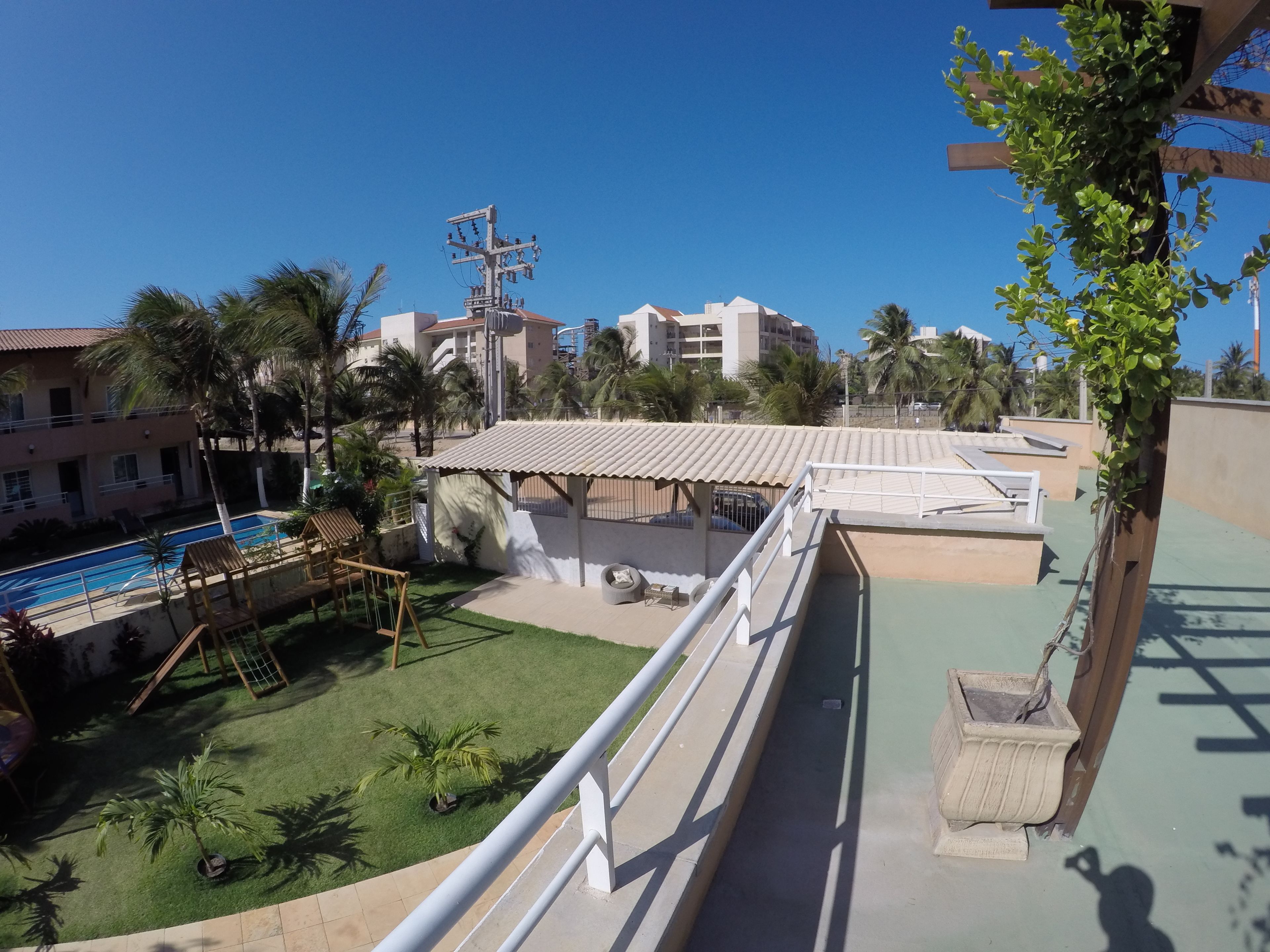 Ένας χώρος πισίνας στην ταράτσα, με έναν μικρό κήπο, μια σκεπαστή περιοχή με καθίσματα και θέα στα γύρω κτίρια.