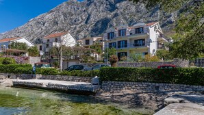 A coastal town with stone buildings, a marina, and a mountain backdrop. - Apartments Miramar (Kotor)