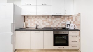 A modern kitchen with white cabinets, a black oven, and a coffee maker. - Apartments Miramar (Kotor)