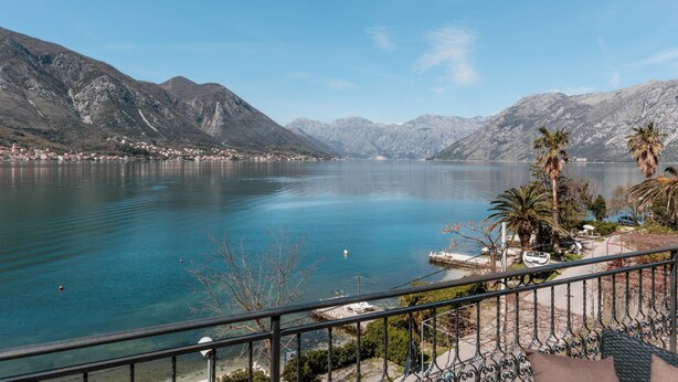A lake with mountains in the background, a clear sky, and a view from a balcony with a railing. - Apartments Miramar (Kotor)