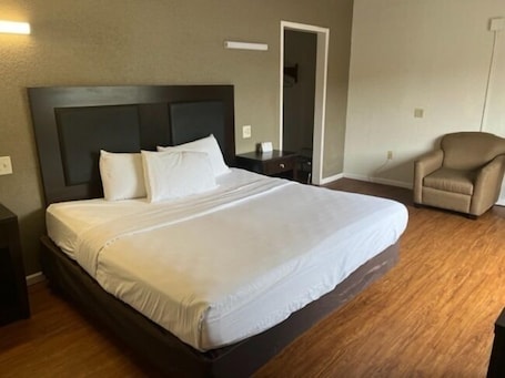 Desk, laptop workspace, bed sheets. Posh Inn & Suites