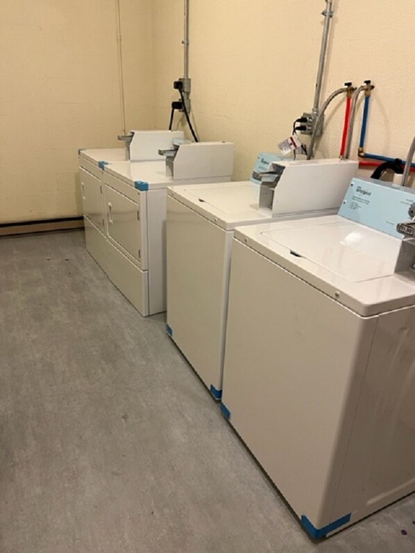 A laundry room with three stacked washing machines and a utility sink.