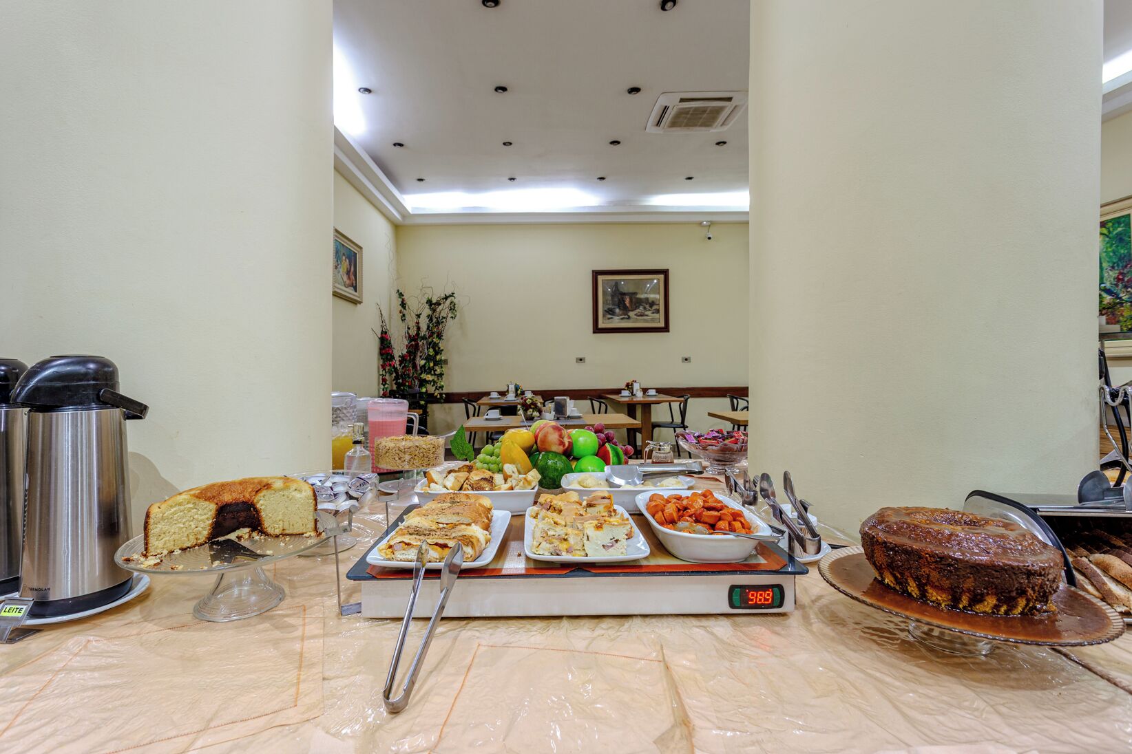 Disposição de buffet com diversos tipos de comida, uma balança e uma máquina de café.