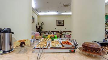 Disposição de buffet com diversos tipos de comida, uma balança e uma máquina de café.