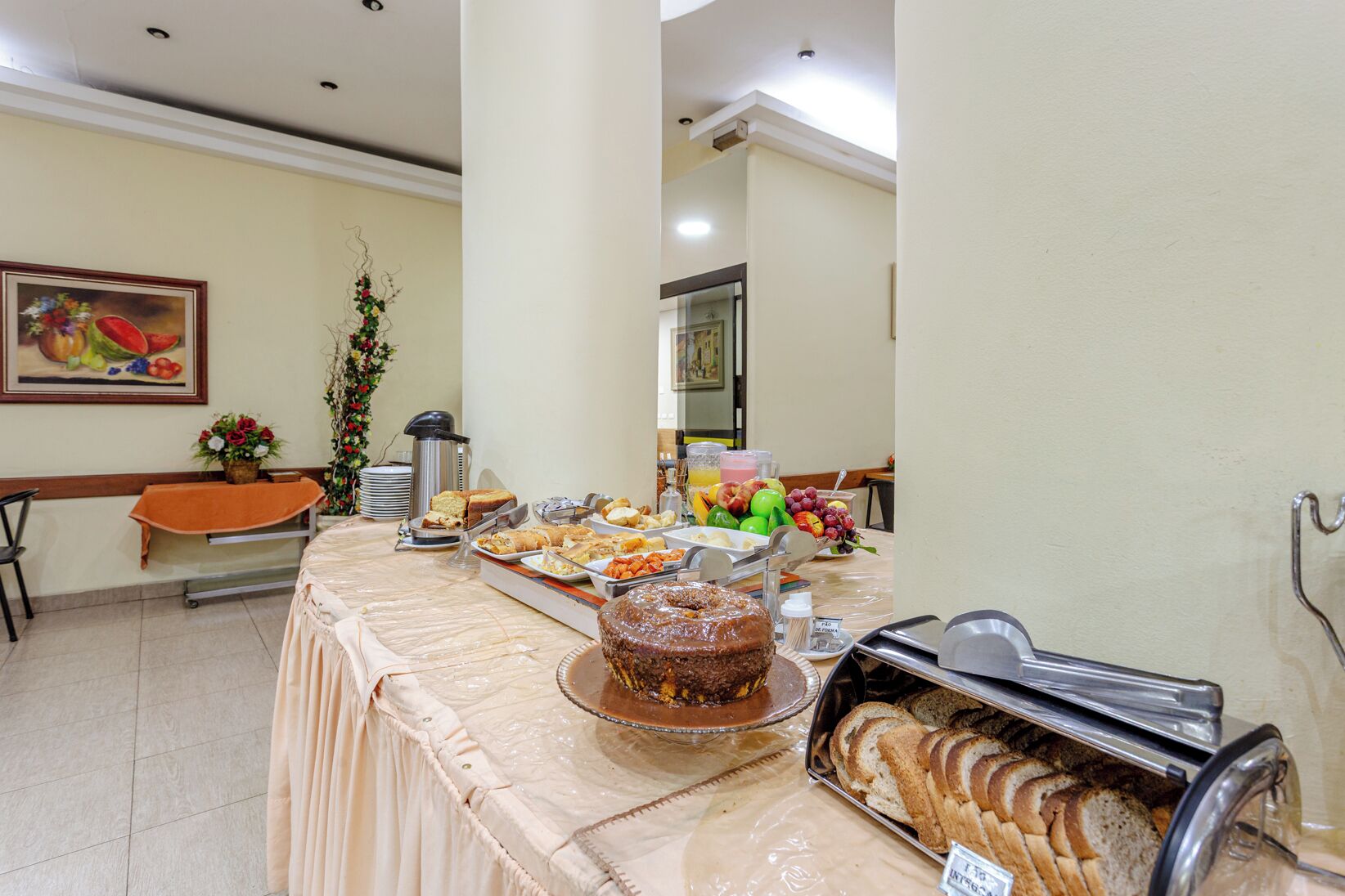 A buffet table with various food items, a coffee pot, and a fruit bowl.