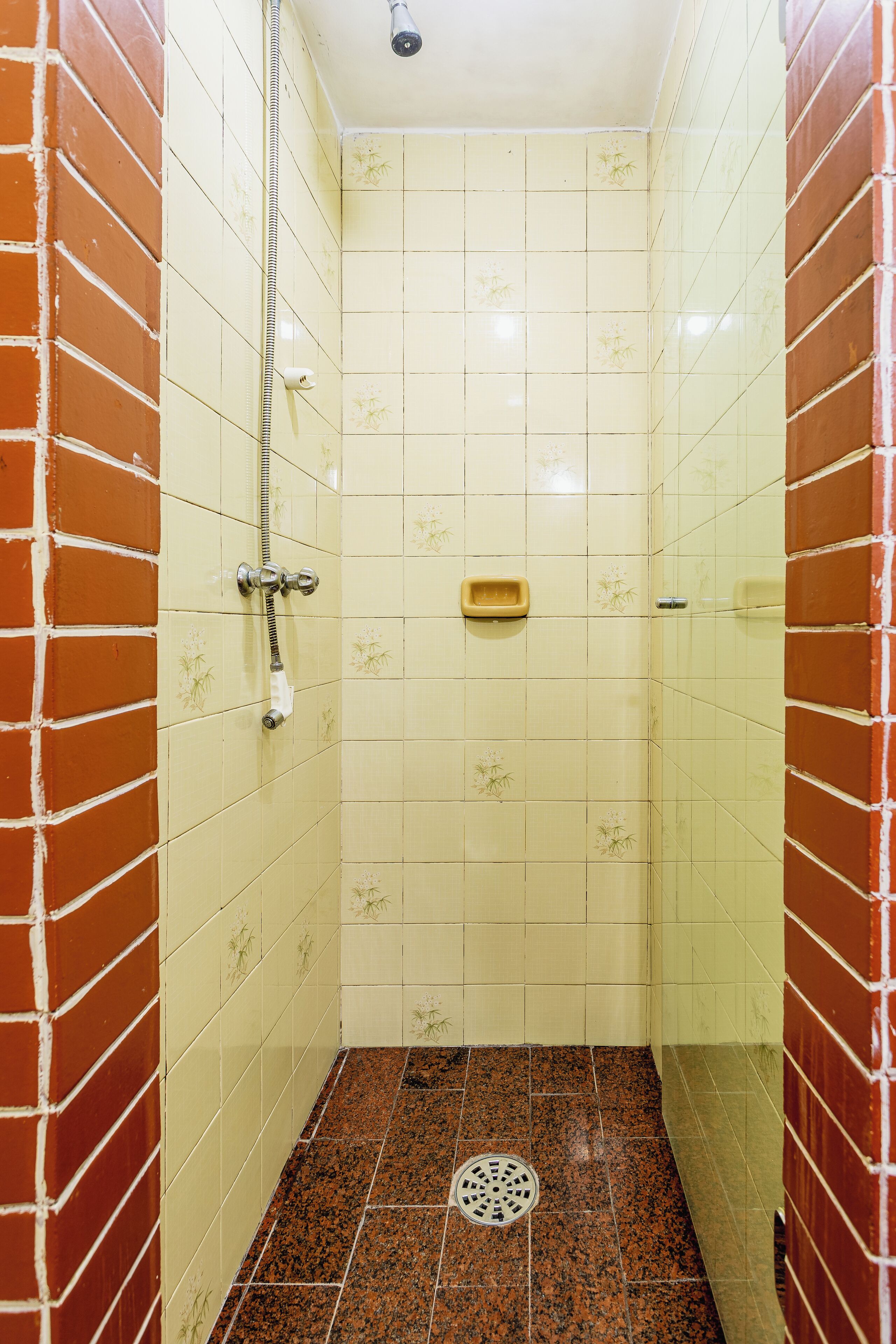 A small, tiled bathroom with a shower, a toilet, and a drain.