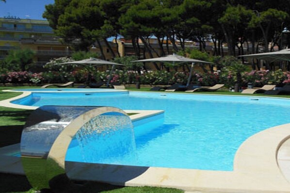 Una piscina al aire libre, sombrillas, tumbonas