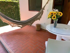 A patio with a hammock, a round table with chairs, and a vase of sunflowers. - Pousada do Mineiro (Porto Seguro)