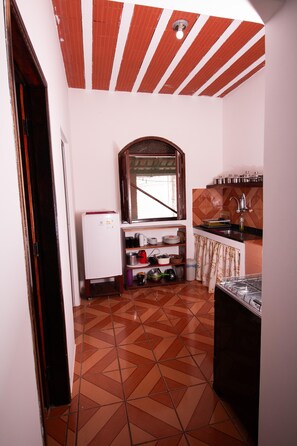 A compact kitchen with a tiled floor, a refrigerator, a sink, and a stove. - Pousada do Mineiro (Porto Seguro)
