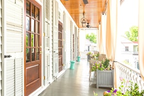 Eine überdachte Veranda mit Holztüren, einem Deckenventilator und Kübelpflanzen.