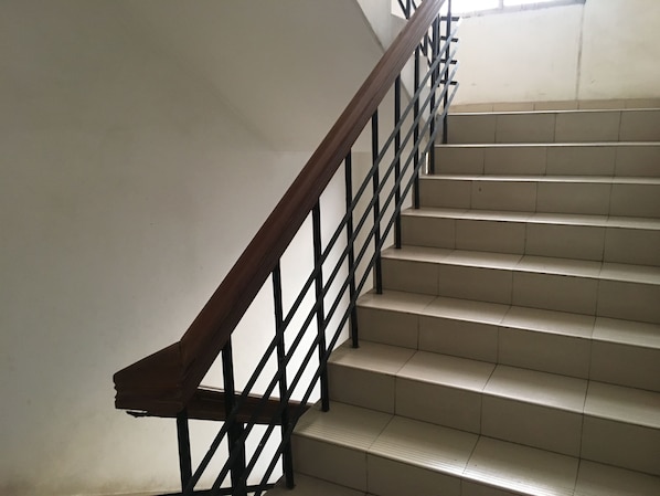 A staircase with a wooden handrail and black metal balusters, leading to an upper floor.