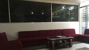 A red sofa set against a white wall with large windows. - Uttara Suite At Dhaka (Dhaka)