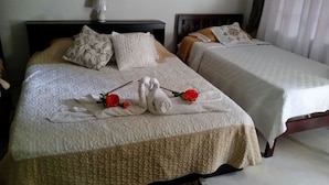 A hotel room with two beds, each with a patterned bedspread and pillows. There are two red roses on the bedspread. - Posada Nativa Licy (San Andrés)
