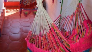 A room with a tiled floor, a hammock, and a hanging plant. - Posada Nativa Licy (San Andrés)