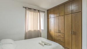 A bedroom with a bed, a wardrobe, and a window with curtains. - Zojo Island (Medellín)