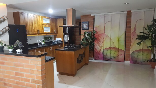 A modern kitchen with wooden cabinets, a black refrigerator, and a central island with a stove. - Zojo Island (Medellín)