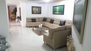 A living room with a beige sectional sofa, a coffee table, and two framed paintings on the wall.