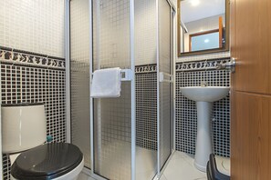 A bathroom with a toilet, a sink, a shower with a glass door, and a mirror above the sink.