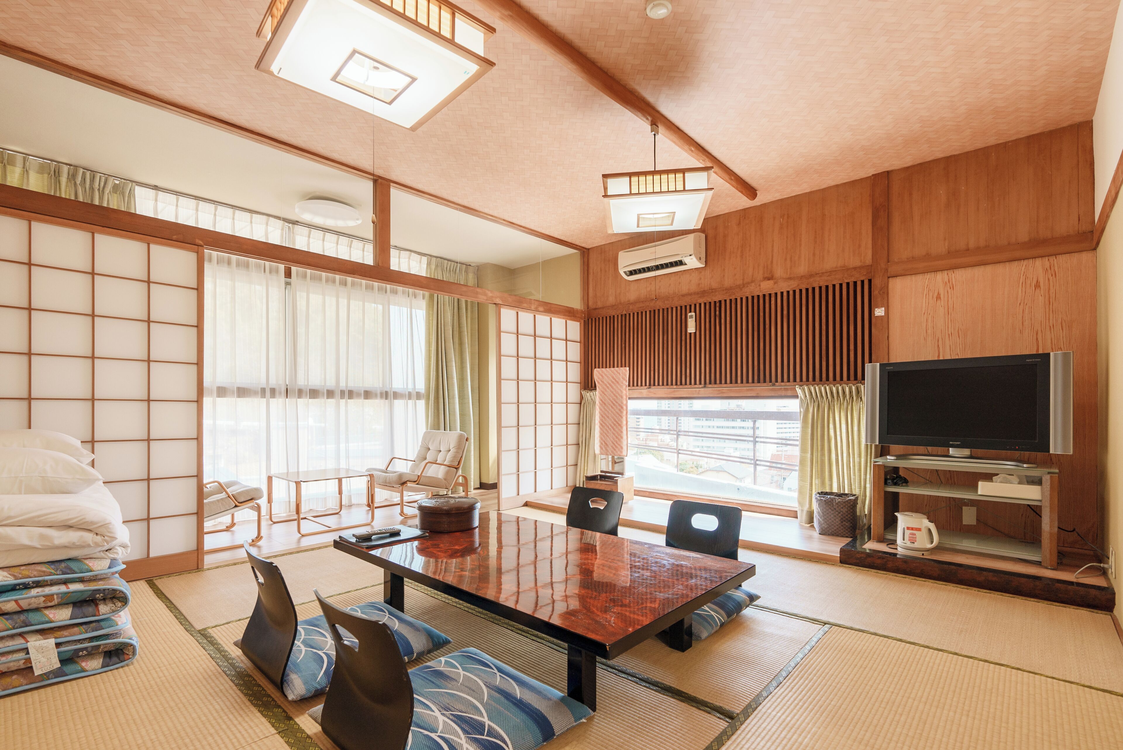 A traditional Japanese-style room with tatami flooring, a low table, and a television.