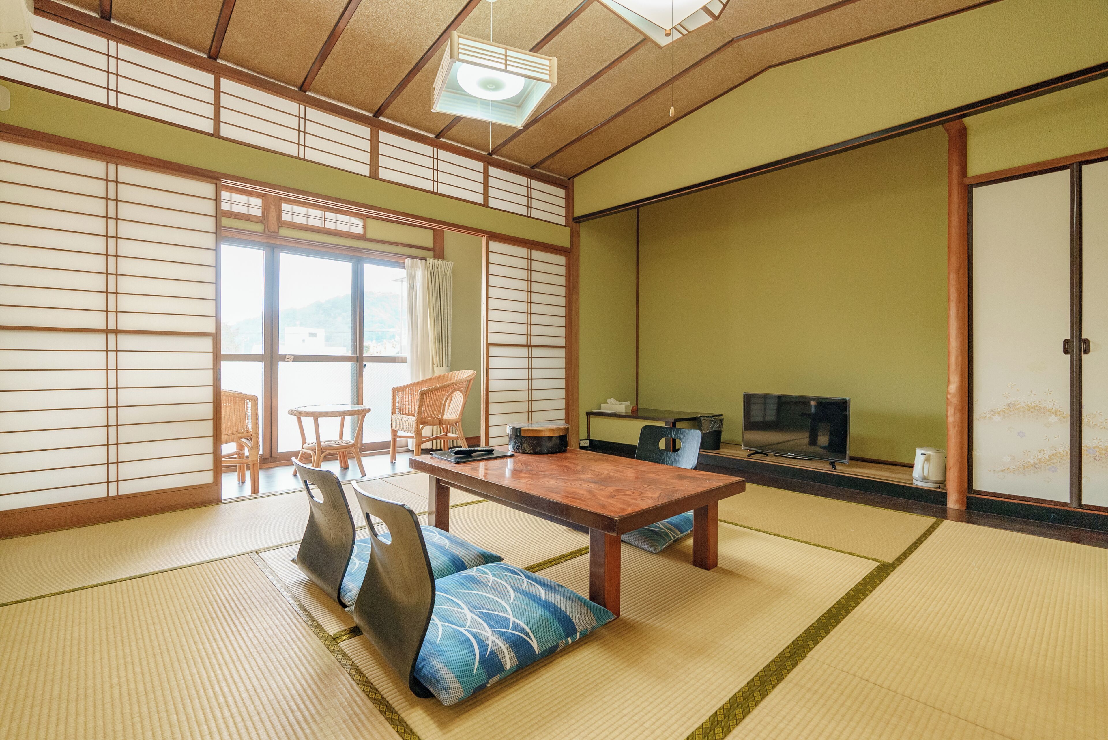 A traditional Japanese room with tatami flooring, a low table, and a television.