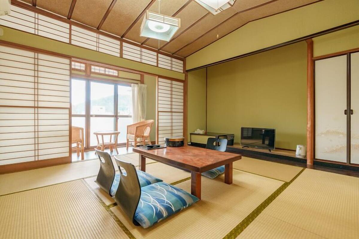 A traditional Japanese room with tatami flooring, a low table, and a television.
