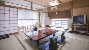 A traditional Japanese-style room with tatami flooring, a low table, seating, and a television. - Atami Kinomiyanoyu Shogetsu (Atami)
