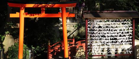A traditional Japanese torii gate with a stone base and a wooden upper structure, surrounded by gravel and greenery.