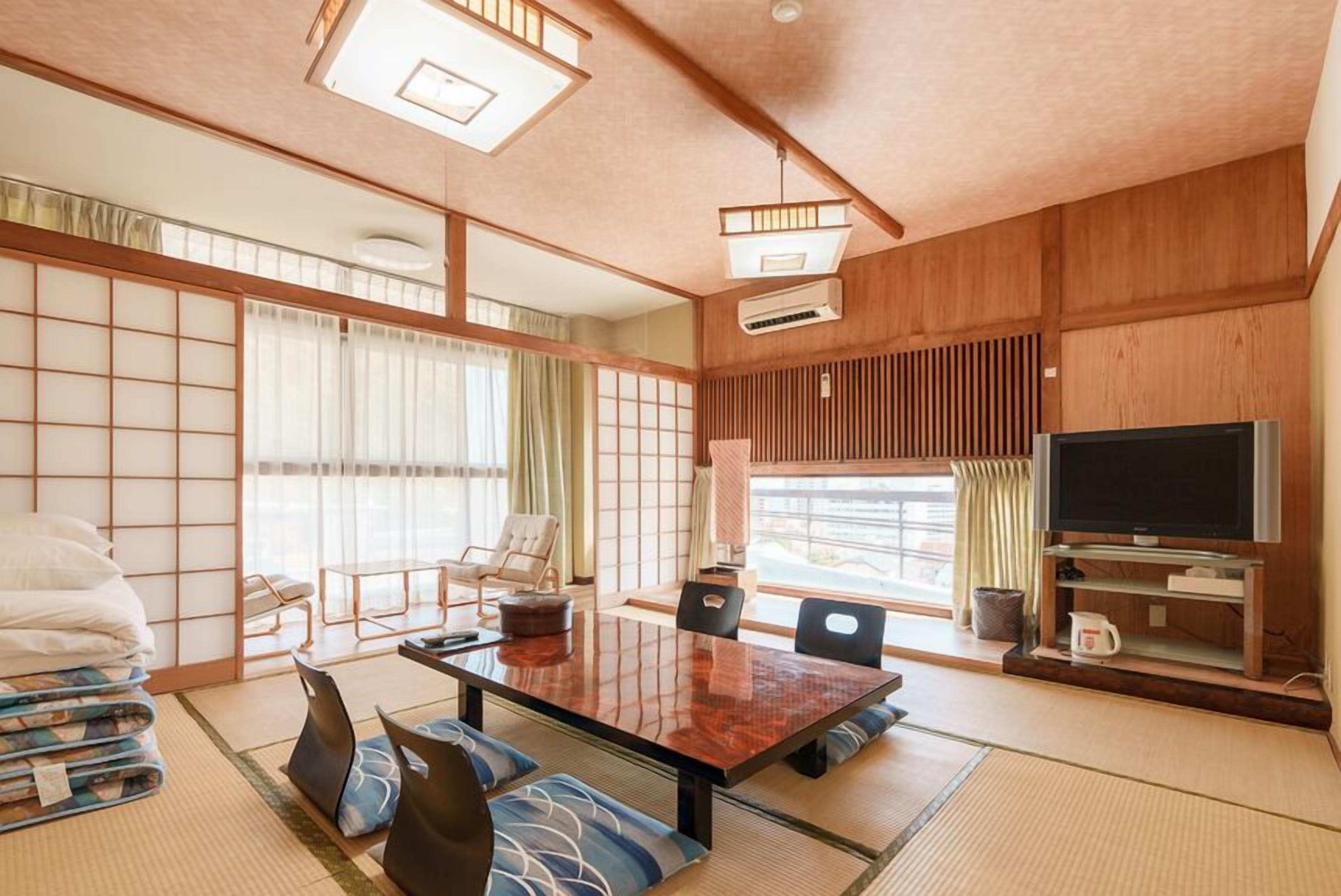 A traditional Japanese-style room with tatami flooring, a low table, and a television.
