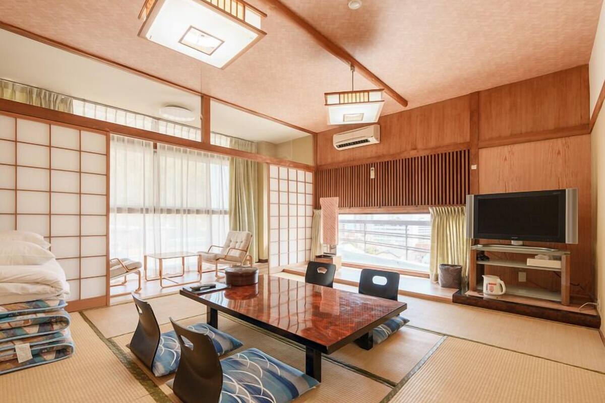 A traditional Japanese-style room with tatami flooring, a low table, and a television.