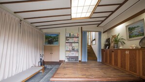 A room with a wooden bench, a bookshelf, a staircase, and a wooden cabinet. - Atami Kinomiyanoyu Shogetsu (Atami)