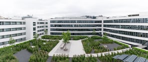 A modern building with multiple floors, a central courtyard with greenery, and a flat roof.