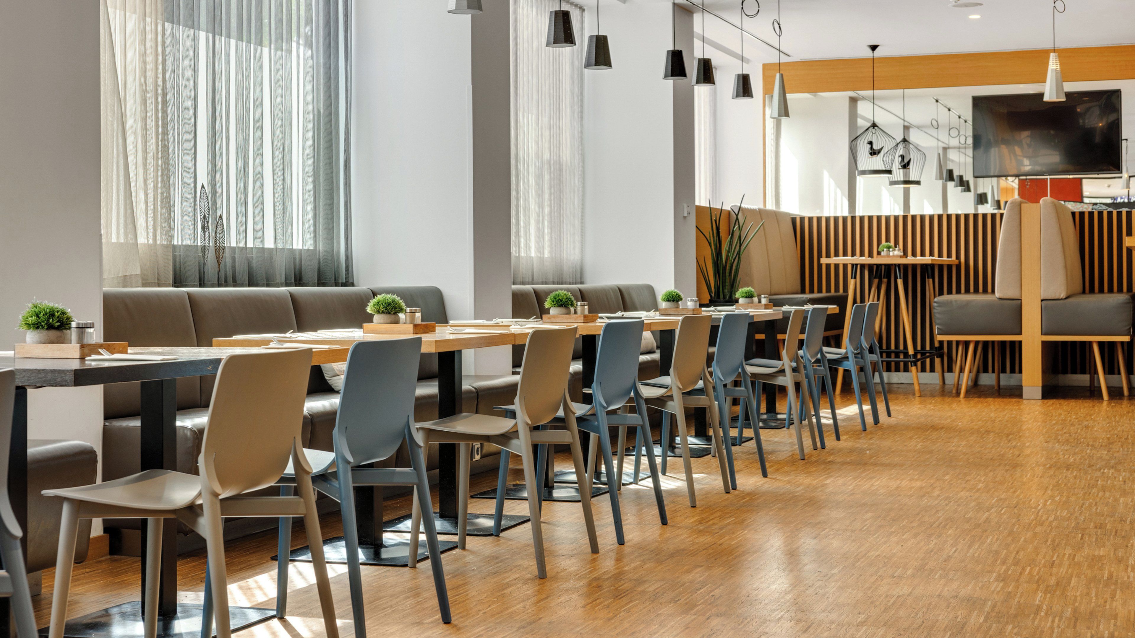A modern dining area with a long wooden table, multiple chairs, and a sofa.