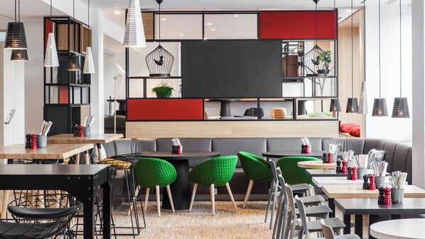 A modern interior with a mix of seating options, including tables and chairs, and a central seating area with a sofa and chairs.