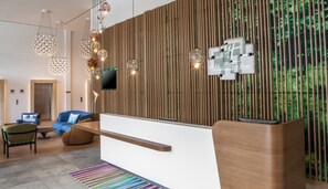 A modern reception area with a wooden slat wall, a flat-screen TV, and a reception desk.