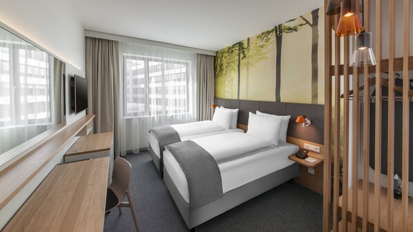 A hotel room with two beds, a desk, a TV, and a large window with curtains. - Holiday Inn Munich - Leuchtenbergring by IHG (Munich)