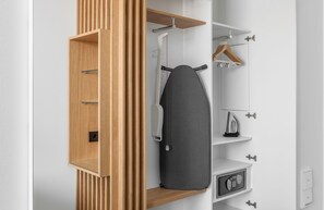A modern closet with a wooden organizer, a hanging rack, and a built-in ironing board. - Holiday Inn Munich - Leuchtenbergring by IHG (Munich)