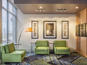 A modern lobby with three green armchairs, a patterned carpet, and framed artwork on the wall. - Holiday Inn Express & Suites Salem North - Keizer by IHG (Keizer)
