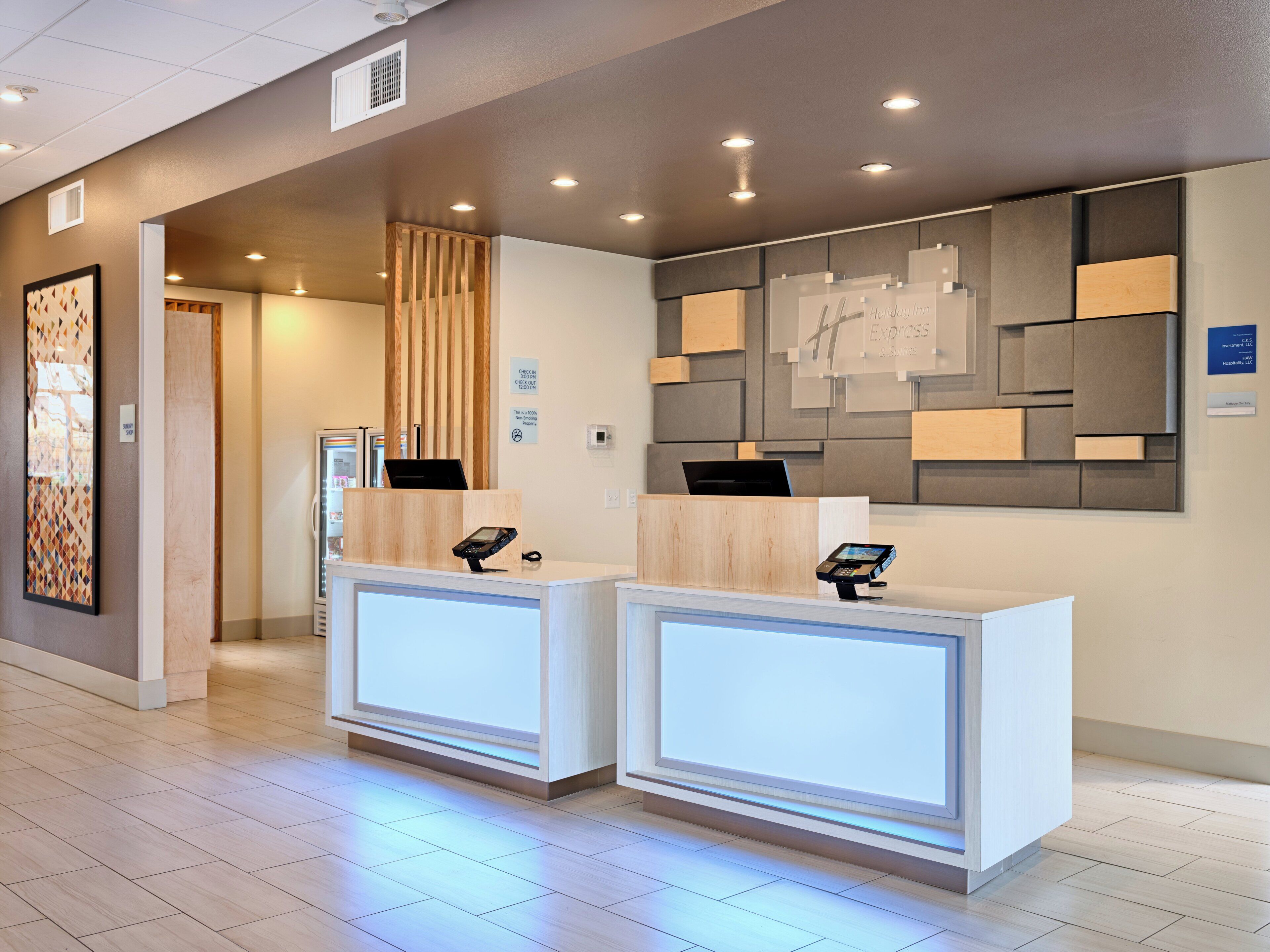 A reception desk with a digital kiosk, a wooden panel, and a wall-mounted display.