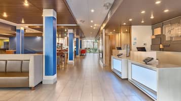 Eine moderne Hotelhalle mit einer Rezeption, einer Sitzecke und einem langen Korridor zu den Zimmern.